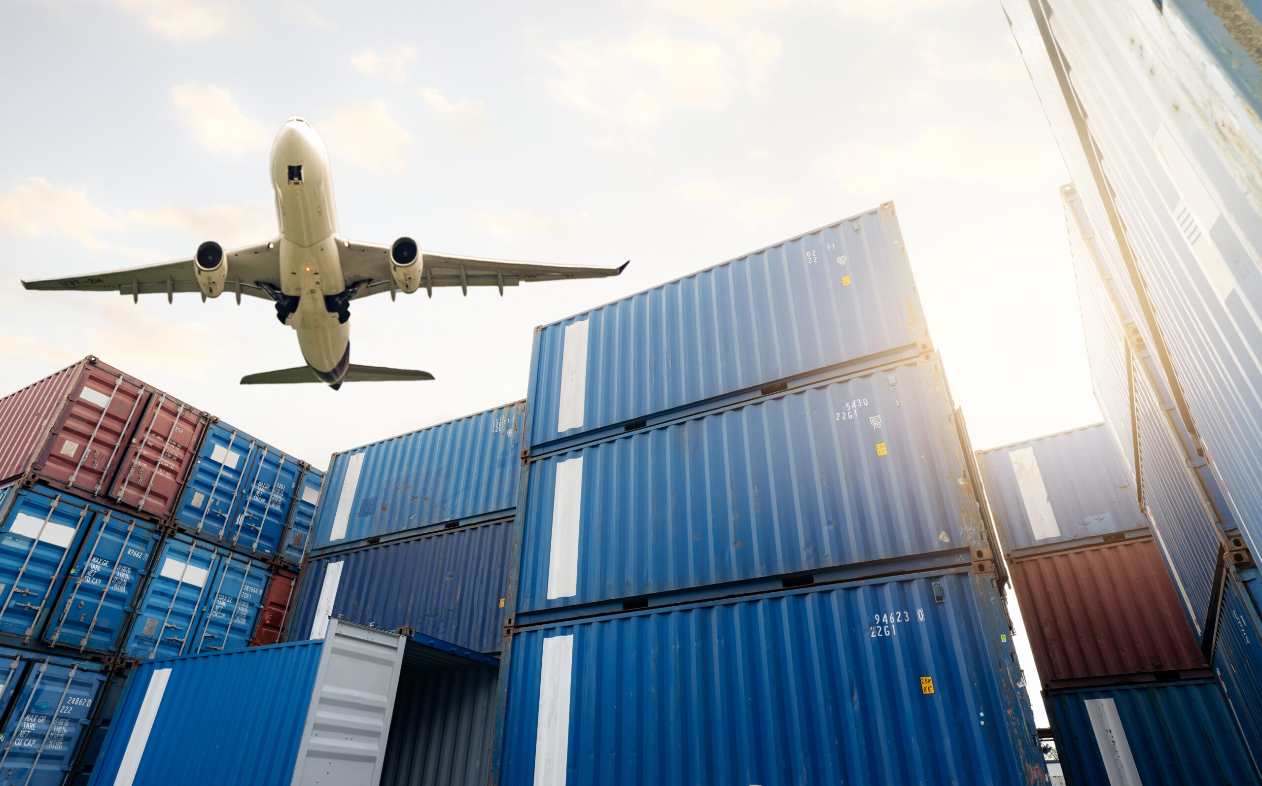 Air logistics. Cargo airplane flying above stack of logistic containers.